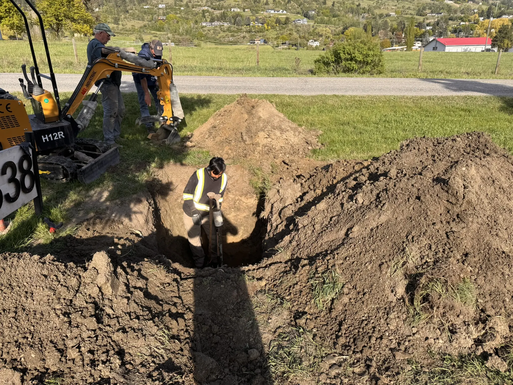 Excavator and crew preparing a septic field trench
