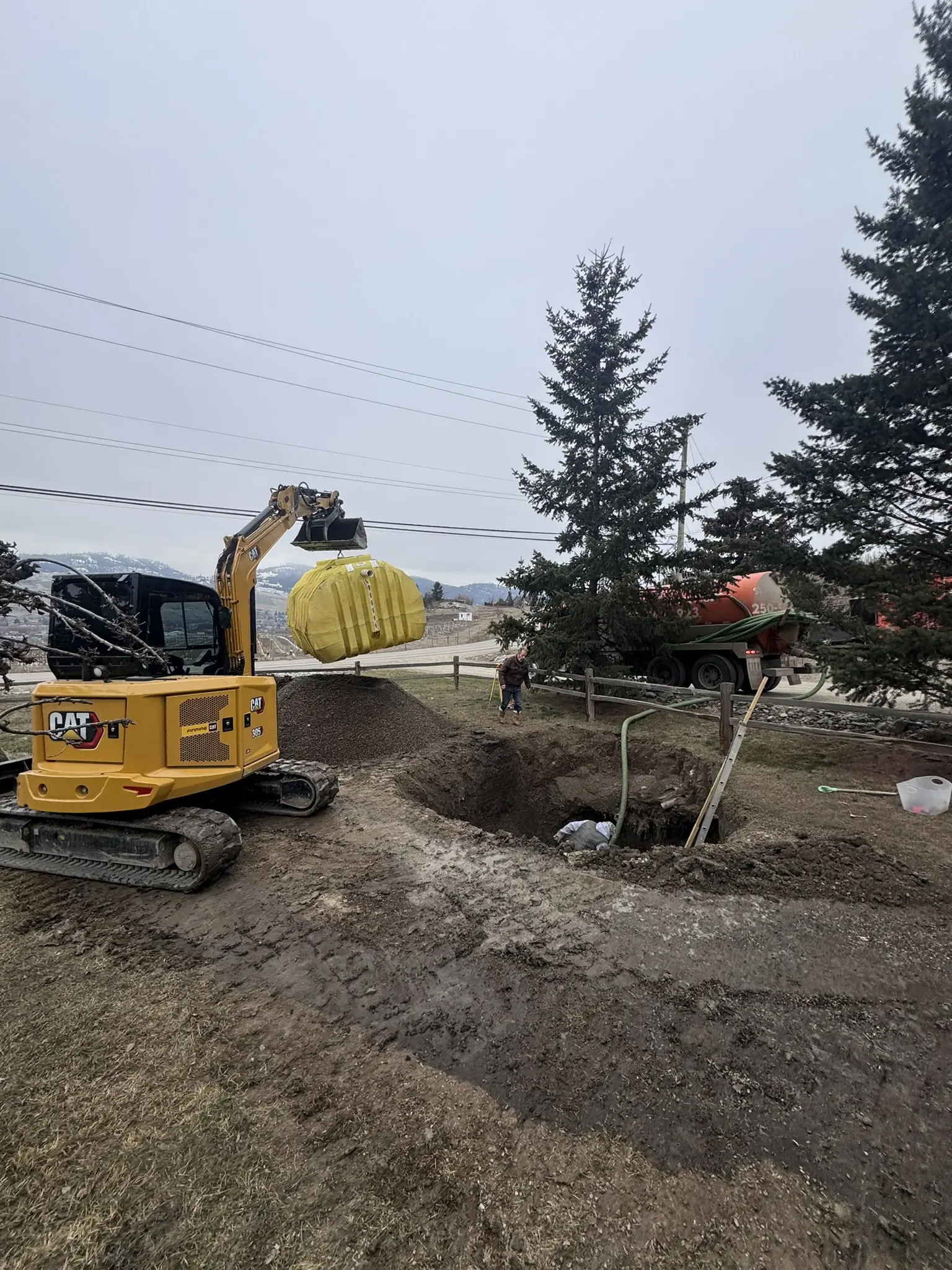 Septic tank installation with excavator and vacuum truck